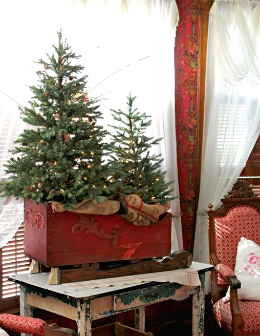 a red box sleigh with Christmas trees with lights and burlap is amazing for rustic holiday decor with a vintage feel