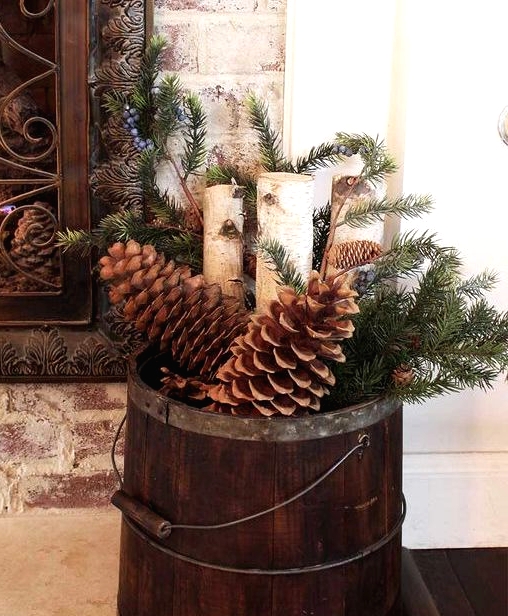 a stained wooden bucket with oversized pinecones, firewood, evergreens is a pretty rustic Christmas decoration to rock