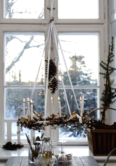 a vine chandelier with greenery, candles and pinecones, a Christmas tree in a crate for a chic Nordic rustic feel in the space