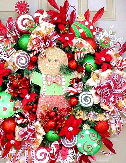 a super colorful and cheerful Christmas wreath with bold red, green and white ornaments, ribbons, fabric blooms and little and large gingerbread men