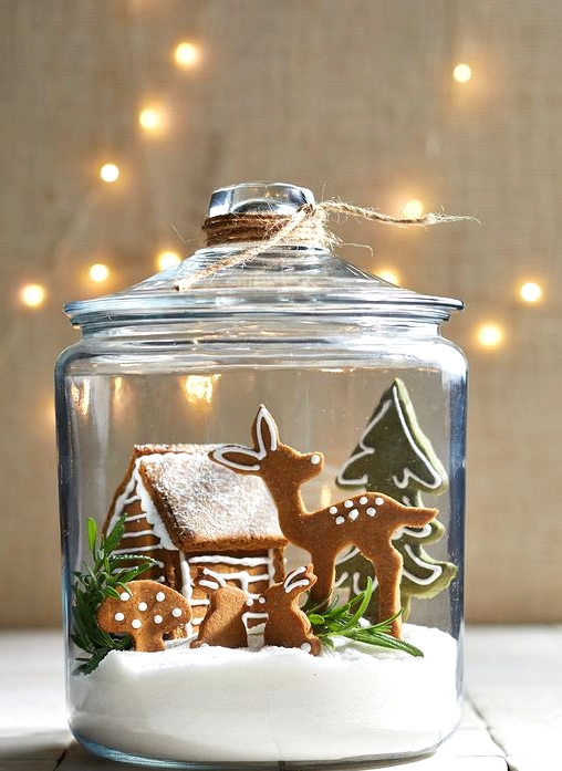 a lovely Christmas terrarium of a jar with faux snow, deer, hare, a small house and a Christmas tree plus greenery