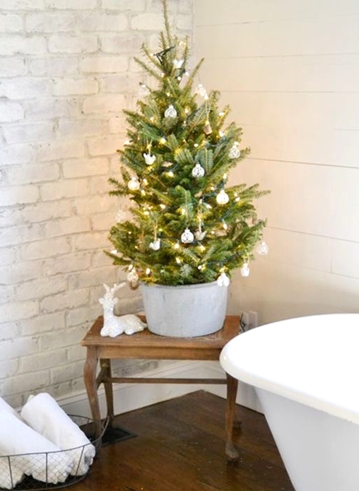 a small Christmas tree in a galvanized bucket, with white and silver ornaments and lights is a pretty idea
