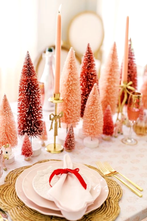 a bold holiday table with red and pink bottle brush trees, pink candles, woven placemats and pink porcelain