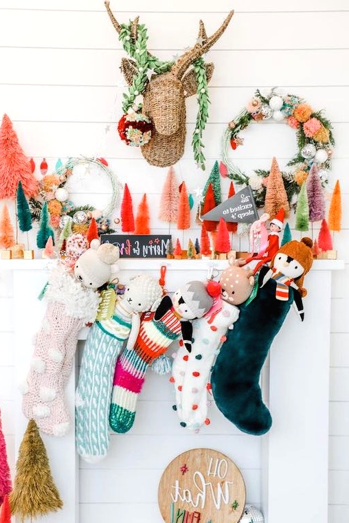 a bright Christmas mantel with colorful bottle brush Christmas trees, a bold wreath, faux greenery and colorful stockings