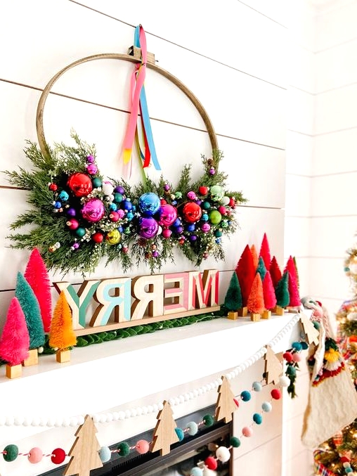 an extra bold Christmas mantel with bright bottle brush trees, letters, a wreath with ornaments and greenery, felt balls and wooden Christmas trees