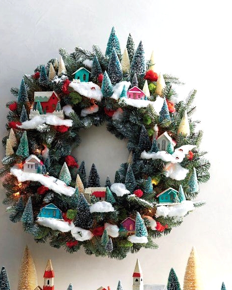 a whimsical Christmas wreath decorated with bottle brush trees, colorful little houses and pompoms is pure fun and chic