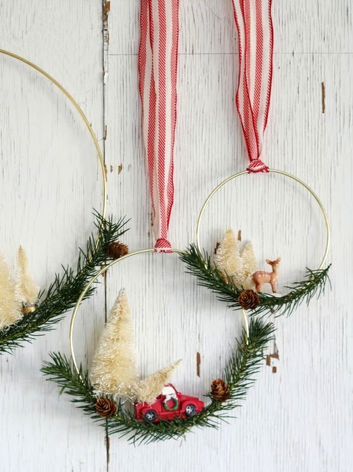 an arrangement of matching metal hoops with evergreens, pinecones, white bottle brush trees and little pinecones