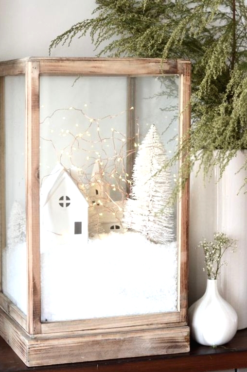 an oversized wodoen candleholder with faux snow, mini houses and churches, a mini bottle brush tree and lights