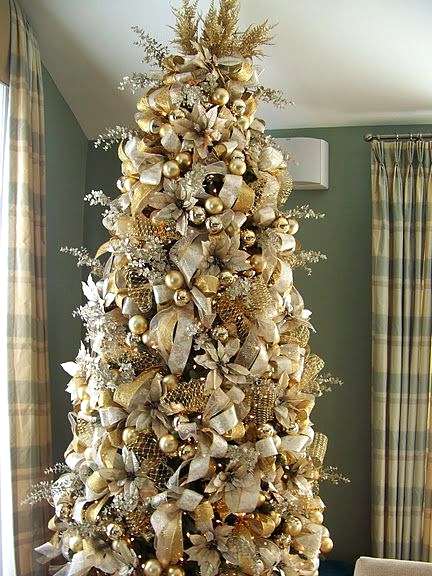 a super refined and glam Christmas tree masterpiece decorated with gold and white ornaments and ribbons, fabric blooms, mesh ribbons and branches
