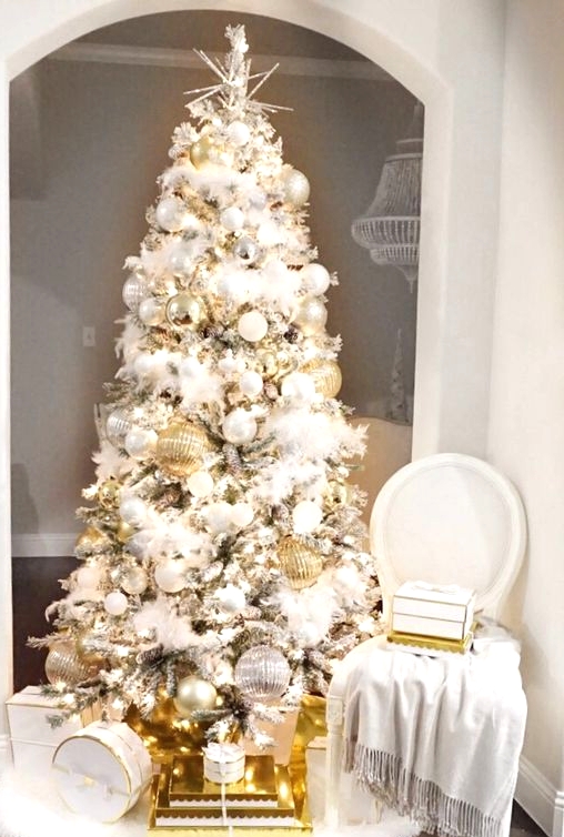 a refined and glam Christmas tree with white and silver plus oversized gold ornaments, lights and a star topper