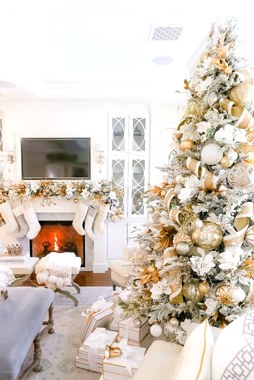 a glam and shiny Christmas tree decorated with white faux blooms, gold and white ribbons, ornaments and leaves