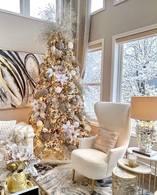 a chic and refined Christmas tree with white fabric blooms, white and gold glitter ornaments, gold glitter ribbons and icy branches on top