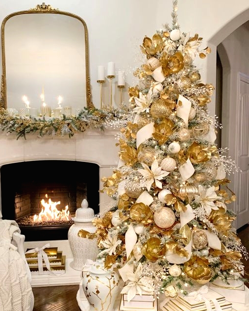 a beautiful Christmas tree fully covered with white and gold ornaments, faux white and gold blooms, icy and gold branches