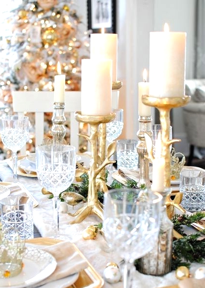 a bright and shiny holiday tablescape with gold and silver ornaments, gold branch candleholders and chargers, evergreens