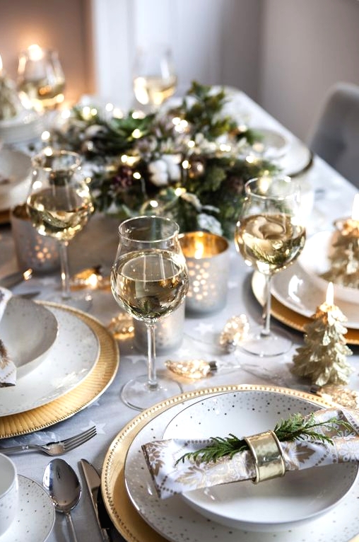 a beautiful and chic Christmas tablescape with polka dot plates and gold chargers, gold Christmas tree candles and lights and gilded candleholders