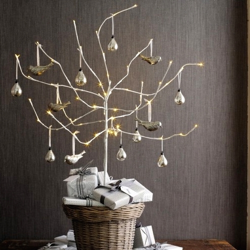 a non-traditional pre-lit Christmas tree with gilded ornaments placed into a basket is a very fresh and bold idea