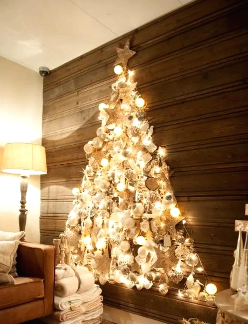 a shiny wall-mounted Christmas tree made with lights on the contour and with lots of silver, pearly and white ornaments inside