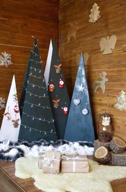 a group of plywood Christmas trees in black and white decorated with lights and ornaments hanging on hooks