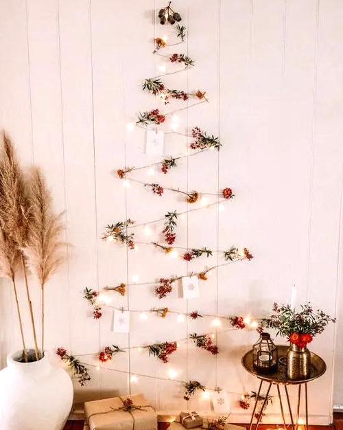 a boho wall-mounted Christmas tree of lights, berries and Christmas cards plus pampas grass and blooms around