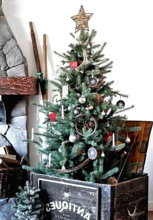 a rustic Christmas tree with antlers, wood slice ornaments, a twig star on top, branches and an antique crate as a base