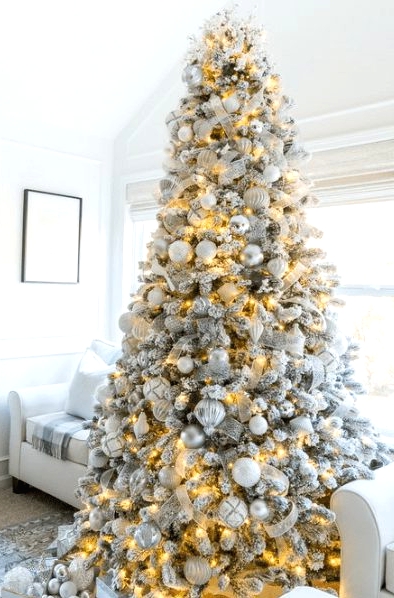 a flocked Christmas tree with metallic and white ornaments, lights and white and silver ribbons is a luxurious piece