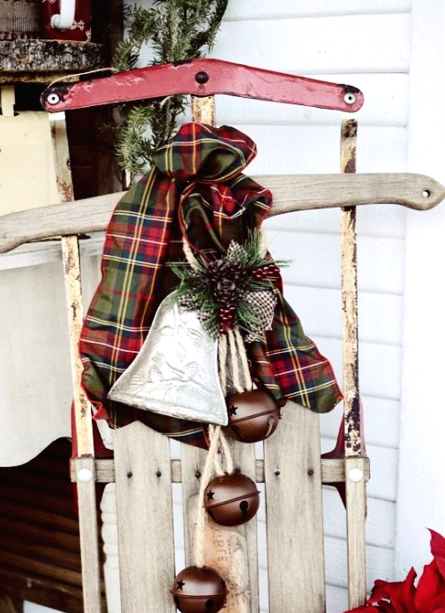 a vintage whitewashed sleigh with a plaid bow and vintage bells is a lovely outdoor decoration for Christmas