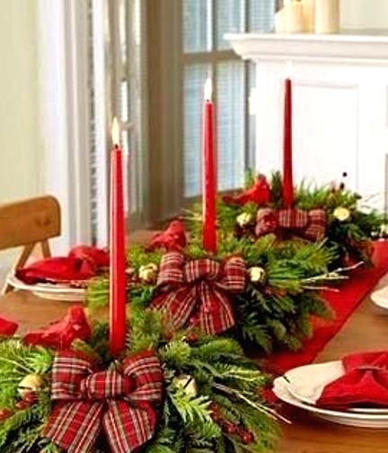 a red table runner, evergreen and red berry arrangements with red plaid bows and red candles dress up the table for Christmas and give it a bright holiday look