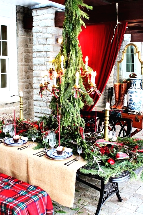 red ribbons on the table and chandelier and a red plaid blanket covering the bench give a bright festive feel to the tablescape