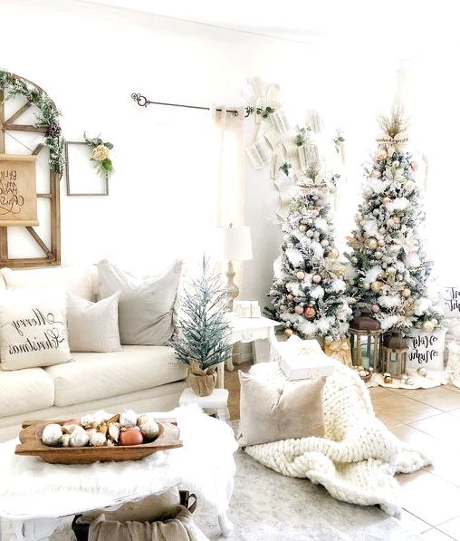 a beautiful winter wonderland Christmas space with trees with metallic ornaments, neutral pillows, chunky blankets, evergreens and ornaments