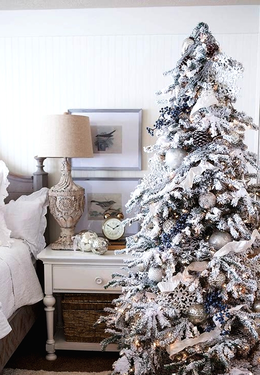 a flocked Christmas tree with privet berries, snowflakes, ribbons, white and silver ornaments and pinecones plus lights is amazing