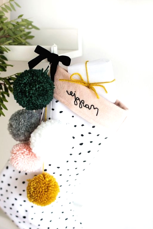 a cute polka dot stocking with muted color pompoms and gifts is a lovely decor idea for a girlish space