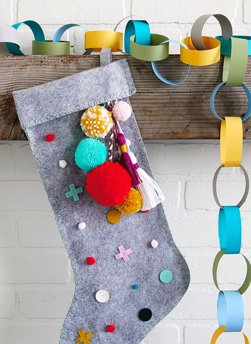 a grey felt stocking with colorful detailing - polka dots, crosses and pompoms and tassels is a lovely DIY piece for a modern space