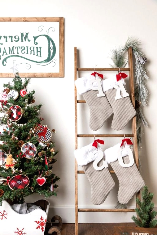 a ladder with tan and white faux fur Christmas stockings, monograms and evergreens is a cool alternative to a mantel with stockings