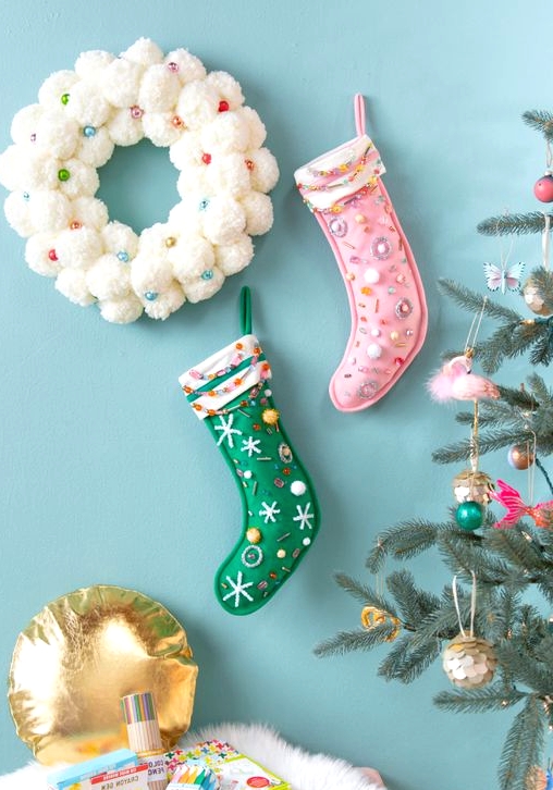 bright pink and green Christmas stockings with bold detailing, embroidery and embellishments and a white snowball wreath with beads