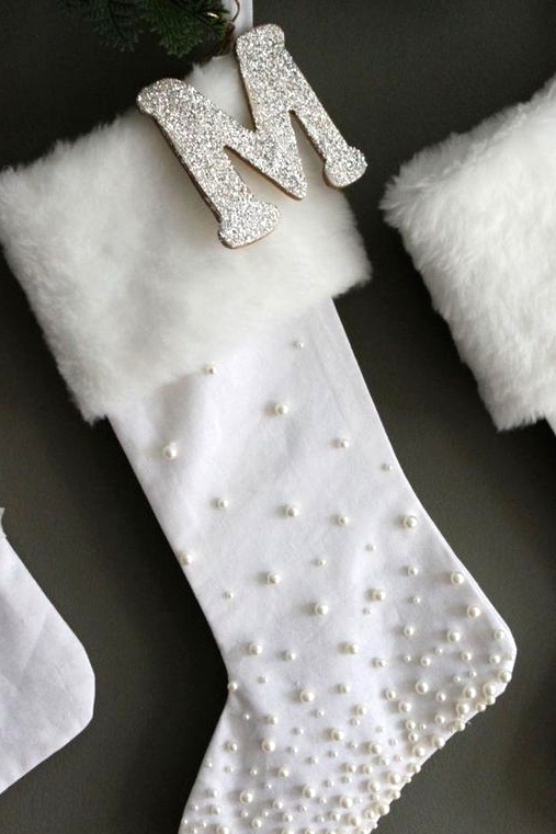 refined white stockings with pearls and white faux fur plus glitter monograms are super refined and chic Christmas decorations