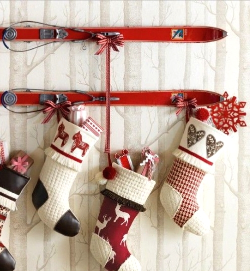 vintage red skis used as holders for black, red and white stockings that holid various gifts can become a nice outdoor or indoor decoration for a vintage-inspired space