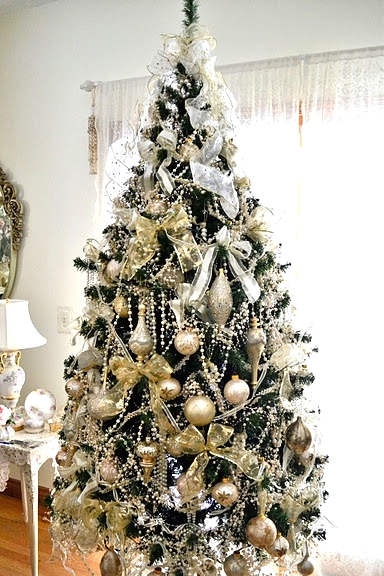 a shiny glam Christmas tree decorated with gold ornaments of various shapes, white bows, pearl beaded garlands is a beautiful idea