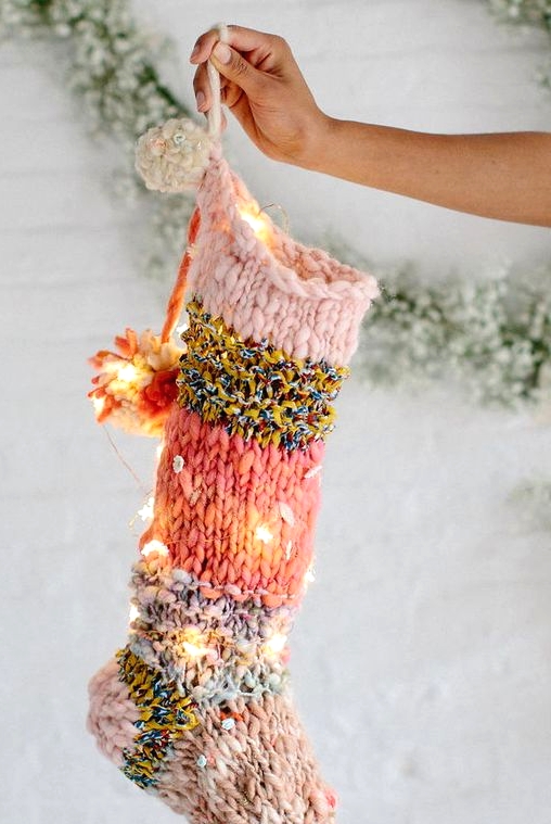 a bright knit Christmas stocking with pompoms and lights integrated is a cool and bold modern decoration for holidays