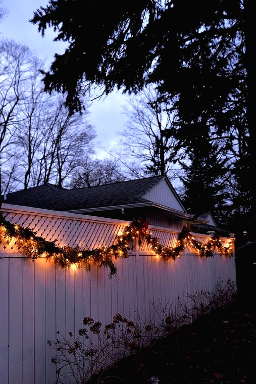 an evergreen and light garland covering the fence gives it a very holiday-like and festive feel