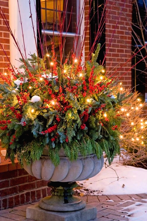 an oversized vintage urn with greenery, evergreens, red twigs and berries is a lovely decoration for outdoors to make a statement at Christmas