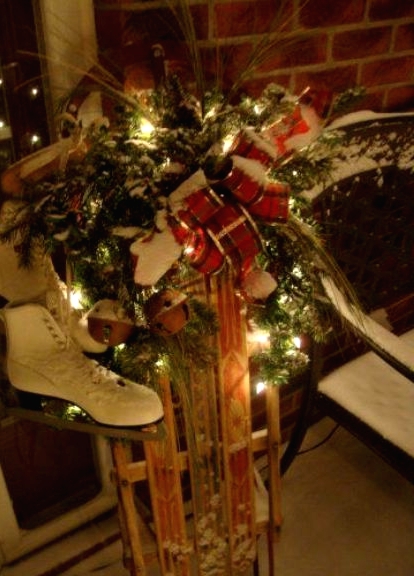 a sleigh with lights, skates, evergreens, bells and a red ribbon bow is a beautiful and cozy Christmas decoration for outdoors