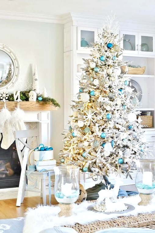 a beach Christmas space with a flocked Christmas tree, light blue and silver ornaments, starfish, an evergreen garland, blues and blue ornaments