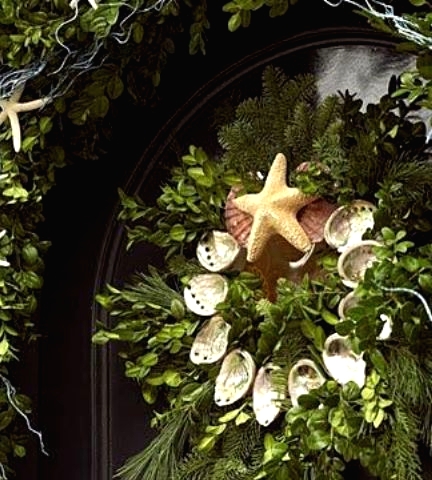 a beach Christmas wreath of greenery, evergreens, seashells and a starfish on top is a lovely idea for a beach home