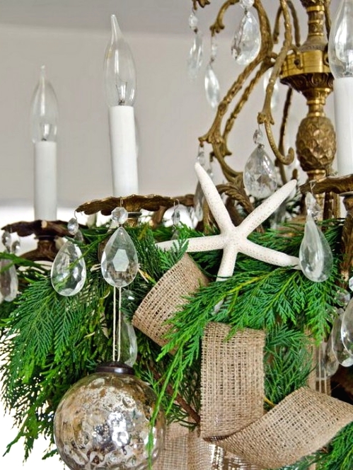 a vintage gilded chandelier with crystals, evergreens, burlap ribbons, mercury glass Christmas ornaments is great for a beach space