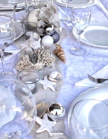 a silver and white beach Christmas tablescape with seashells, starfish, corals and neutral tableware and linens