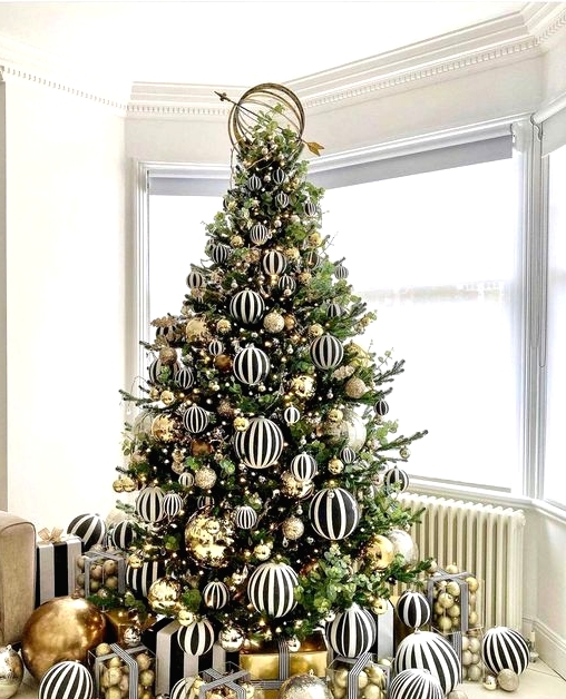 a jaw-dropping modern Christmas tree decorated with black and white striped and gold large-scale ornaments is amazing