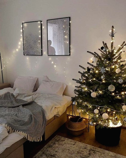 a modern Christmas tree with black, white and silver ornaments, with lights in a black bucket with lights is a cool idea