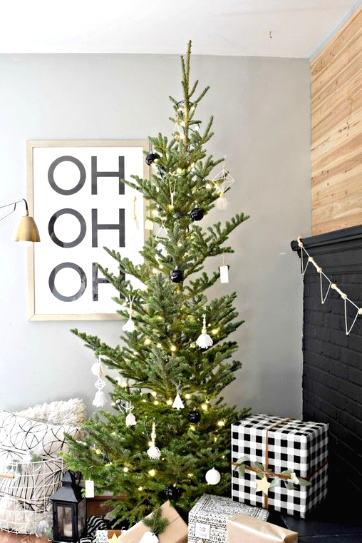 a modern Christmas tree with white and black ornaments and lights is a stylish idea that will fit a Scandinavian space, too