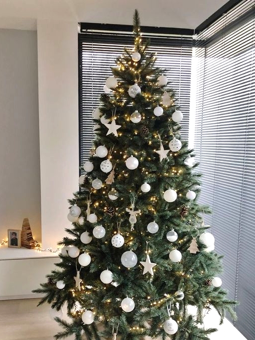 a modern Christmas tree with white baubles and stars, pinecones and lights is a chic idea with a trendy feel