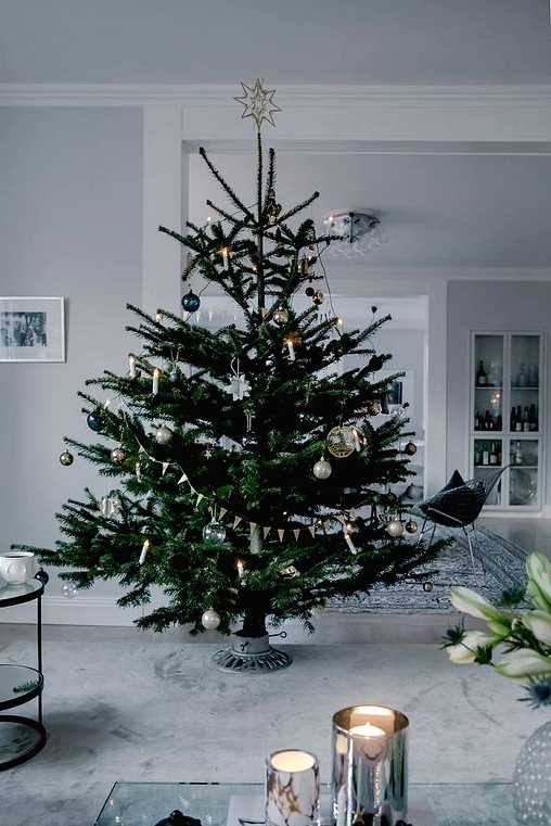 a modern Scandi Christmas tree with navy, silver, green and clear ornaments plus lights and buntings is a beautiful idea